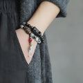 Men's black hair bracelet with white crystal tassel showing ethnic design and adjustable sizing