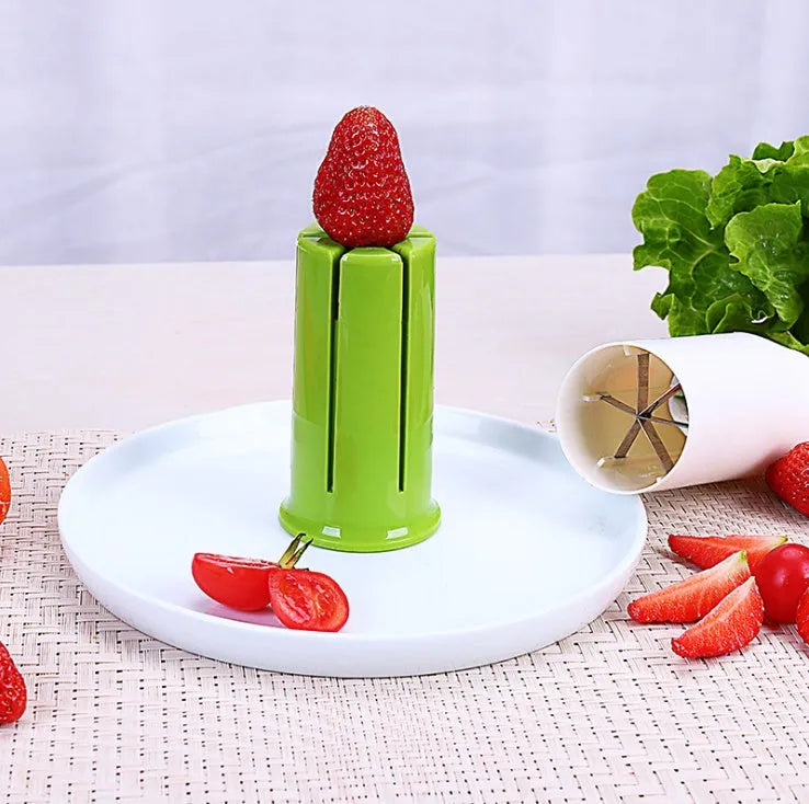 White plastic vegetable and fruit slicer with multiple stainless steel blades for cutting cucumbers, carrots, and strawberries.