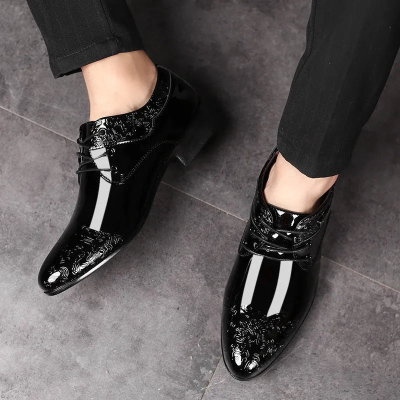 Glossy black men's business formal shoes with patent finish, pointed toe, and carved detail on a neutral background