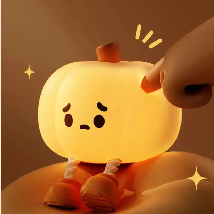 Soft orange silicone pumpkin-shaped night light with a warm glow on a bedside table.