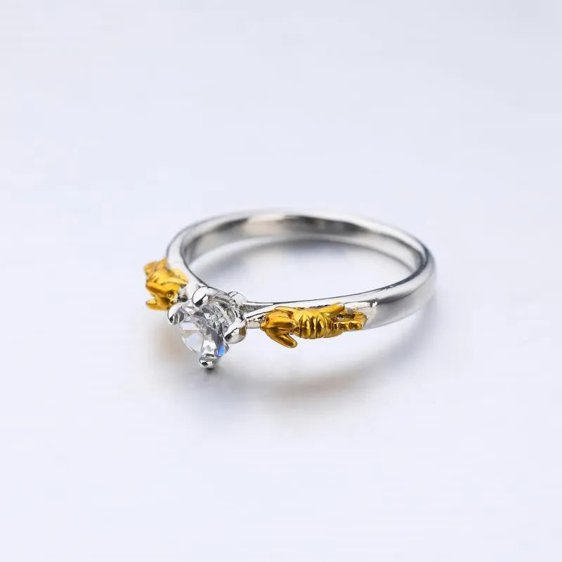 Copper crown-shaped crystal ring in a black gold tone on a neutral background.
