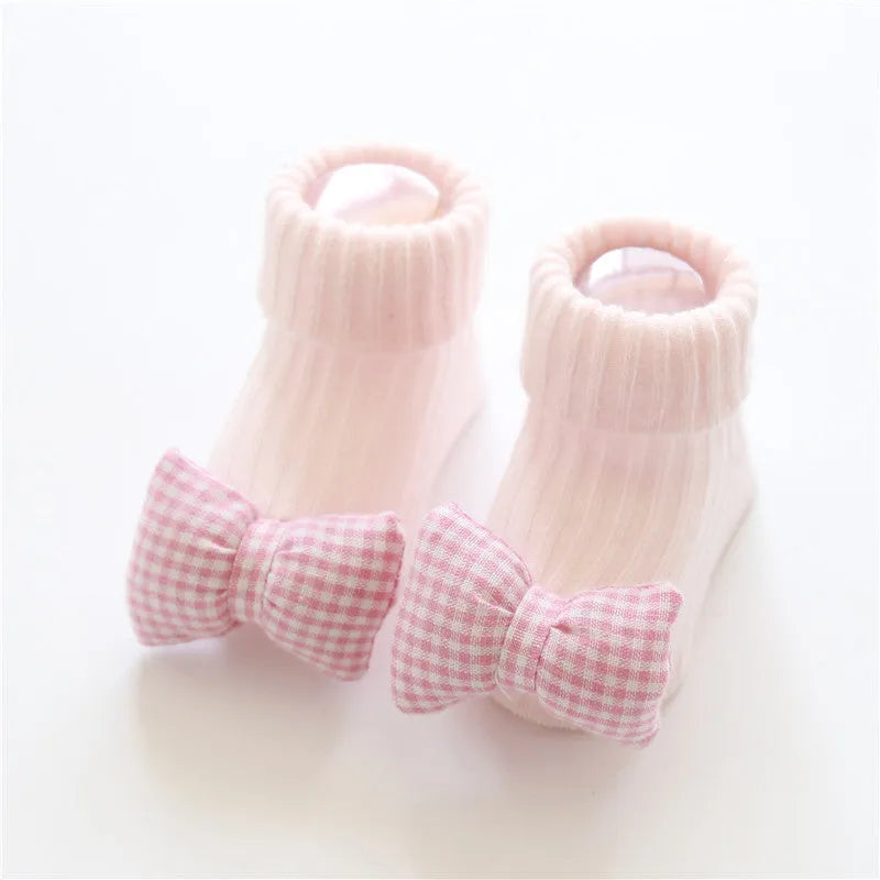 Cotton baby floor socks in a pink bow pattern, shown on an infant's feet.