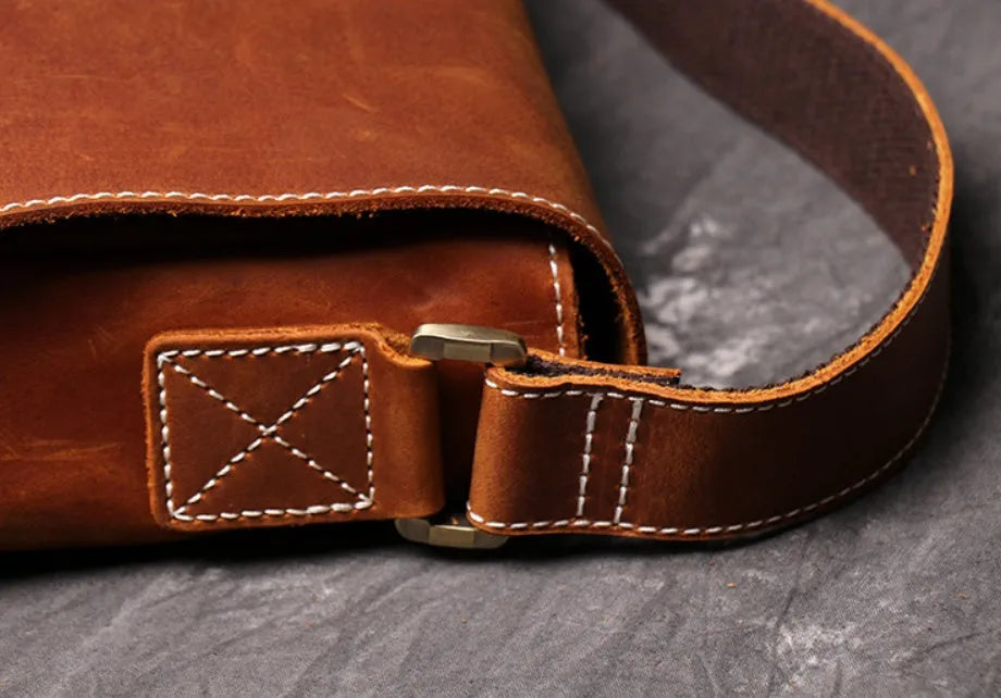 Vintage brown cowhide men's messenger bag showing front flap and adjustable shoulder strap