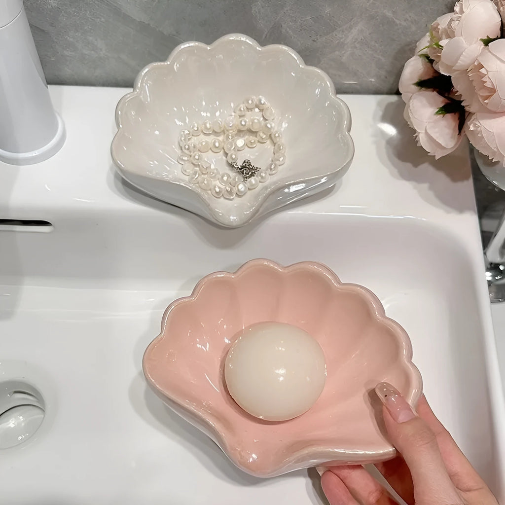 White shell-shaped plastic soap dish for bathroom counter next to sink.