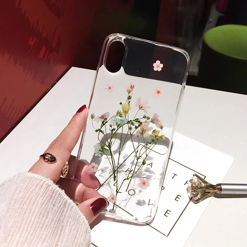 Clear handmade TPU iPhone case with pink dried flowers encased in epoxy resin on the back.