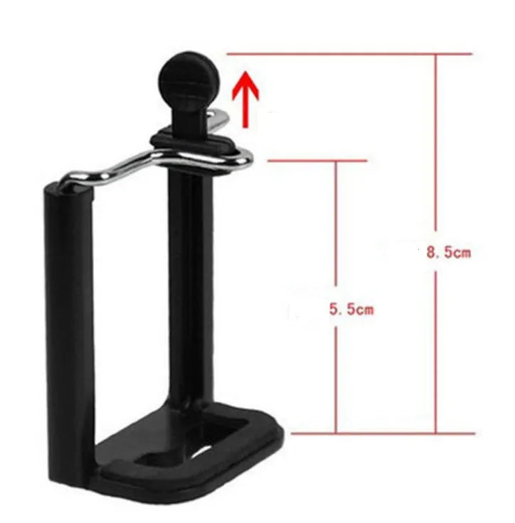 Black mini flexible tripod extended on a table with a silver U-shaped phone clip attached.