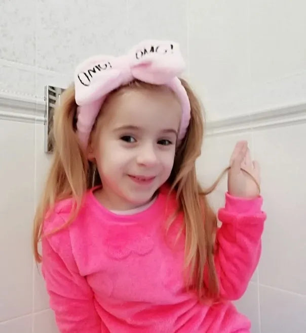 Coral velvet butterfly end hair band with letter text design in pink colour on neutral background