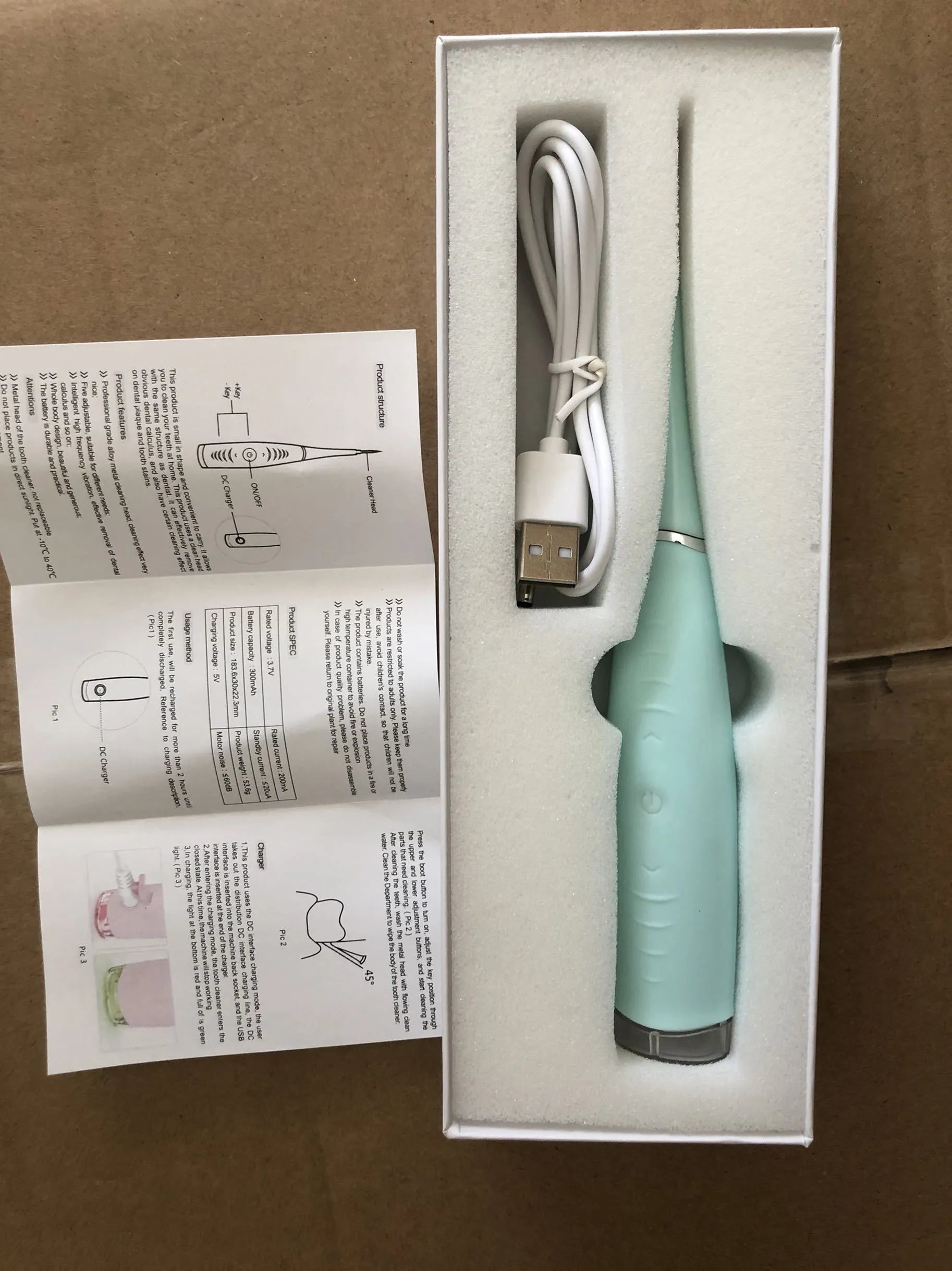 Pink and blue electric dental scaler tool with silicone handle on a bathroom counter.