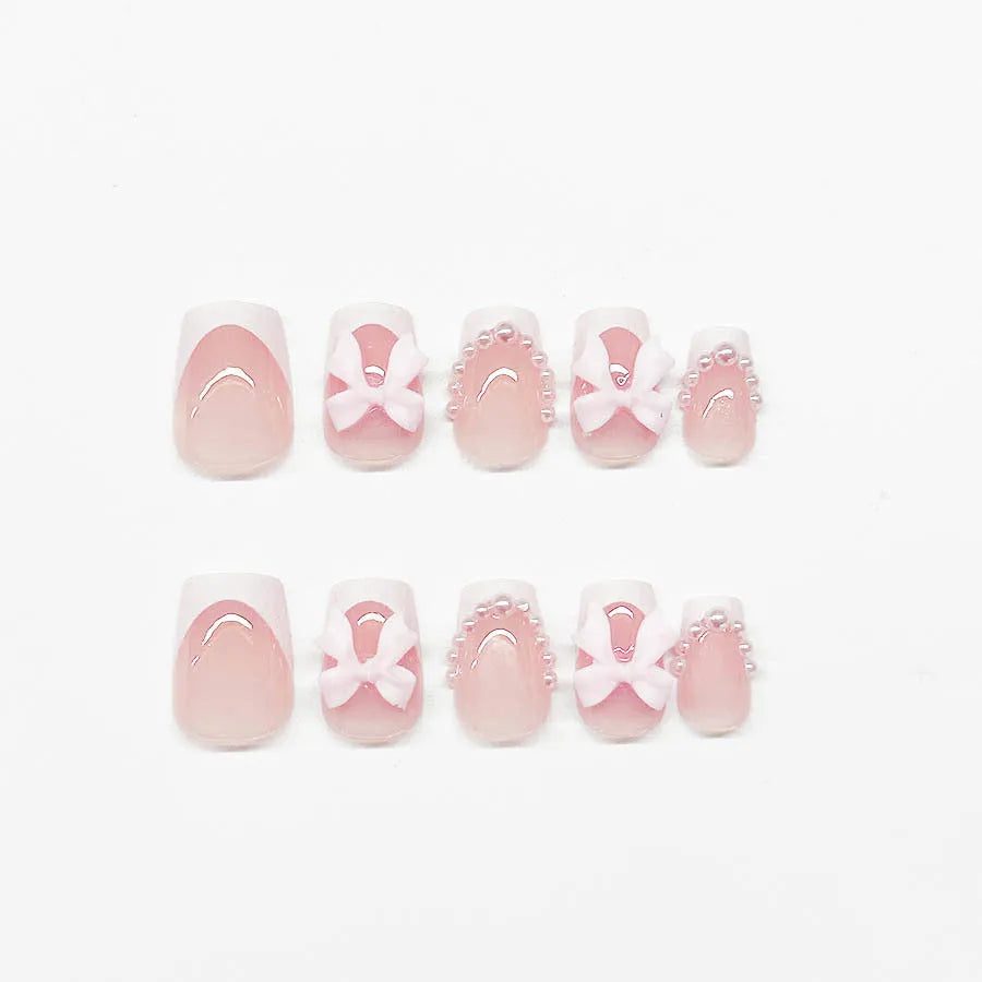 Short white French tip false nails with cute bow and starry sky designs, shown with glue bottles.