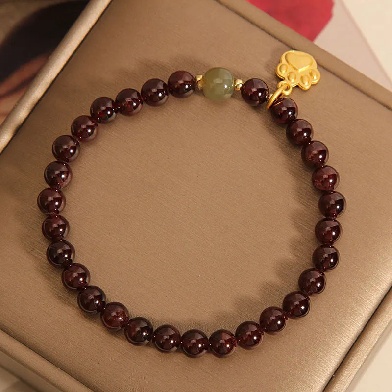 Women's original design Cat's Paw Garnet crystal bracelet on a plain background.