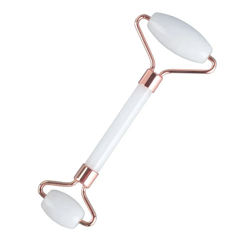 White jade facial roller and gua sha scraper tools placed on a smooth wooden storage board.