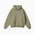 A man wearing a loose-fit, grey cotton hooded pullover sweater with drop-shoulder sleeves.