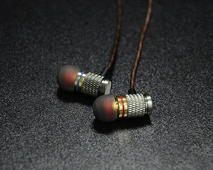 Close-up of wired in-ear headphones with metal earpiece, silicone cable, and 3.5mm L-bend plug.