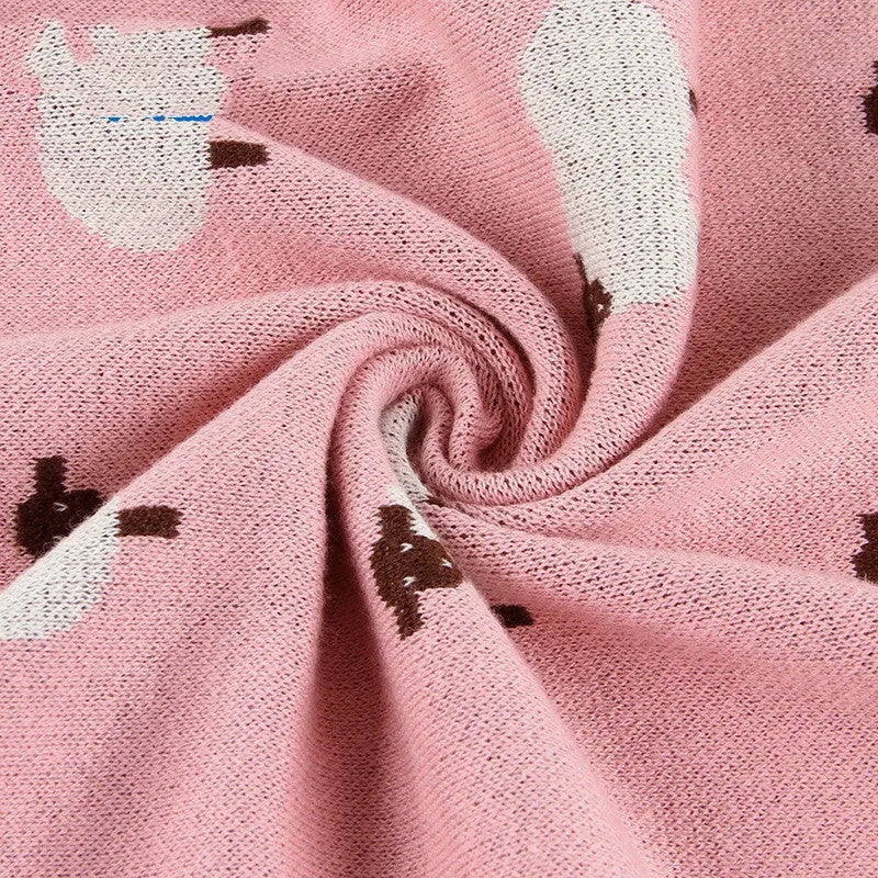 A pink baby sheepskin blanket measuring 100 by 80 cm on a pram.