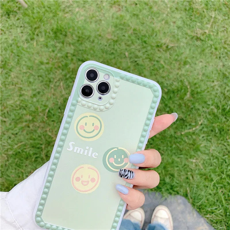 Green TPU iPhone case showing geometric smiley face design with polka dot frame on back