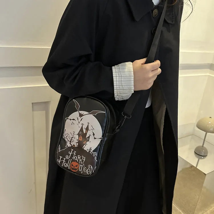 Black Halloween crossbody bag with cartoon pumpkin, ghost, and bat print, showing front and strap.