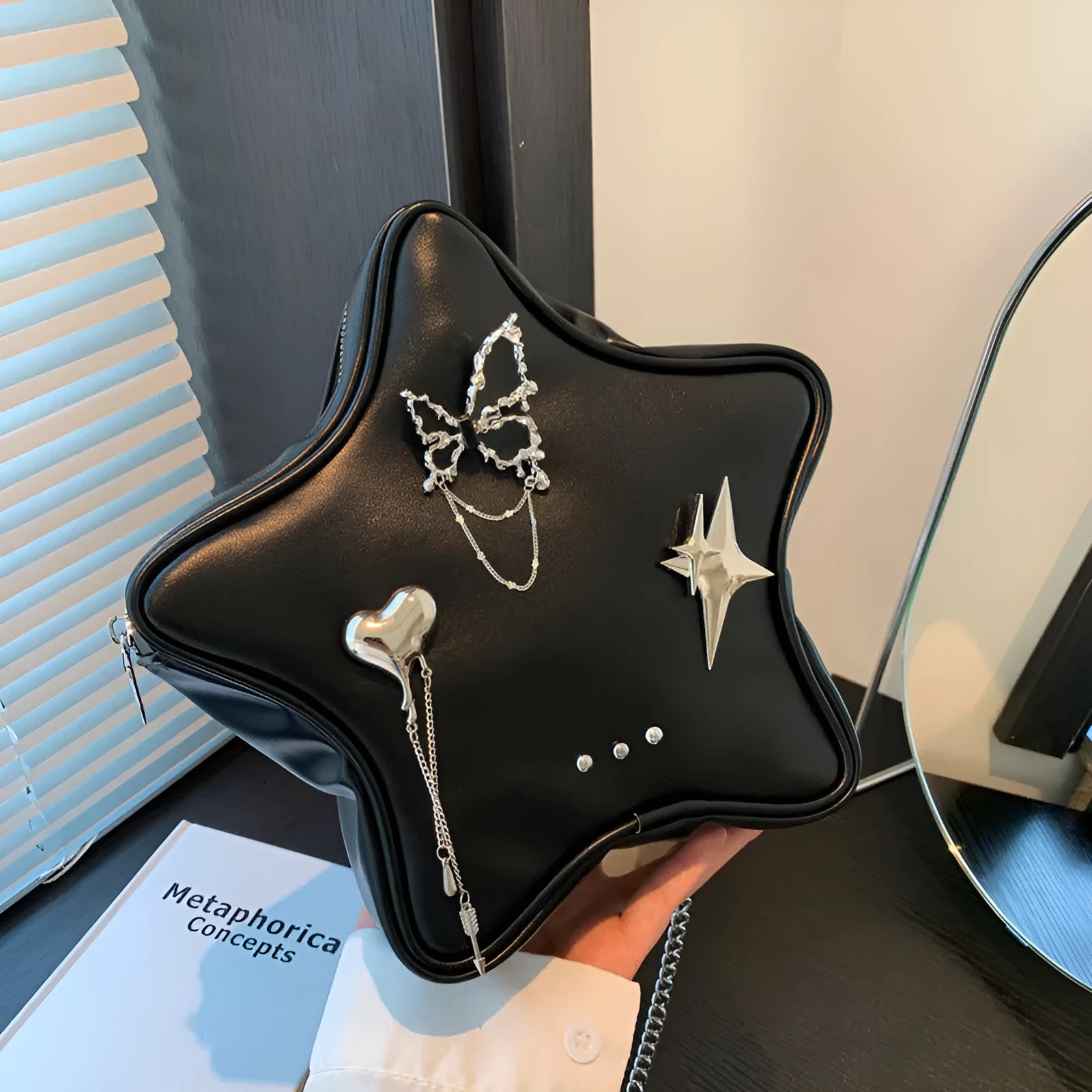 Black PU leather backpack with metal butterfly pendant and chain accents showing three-dimensional pockets