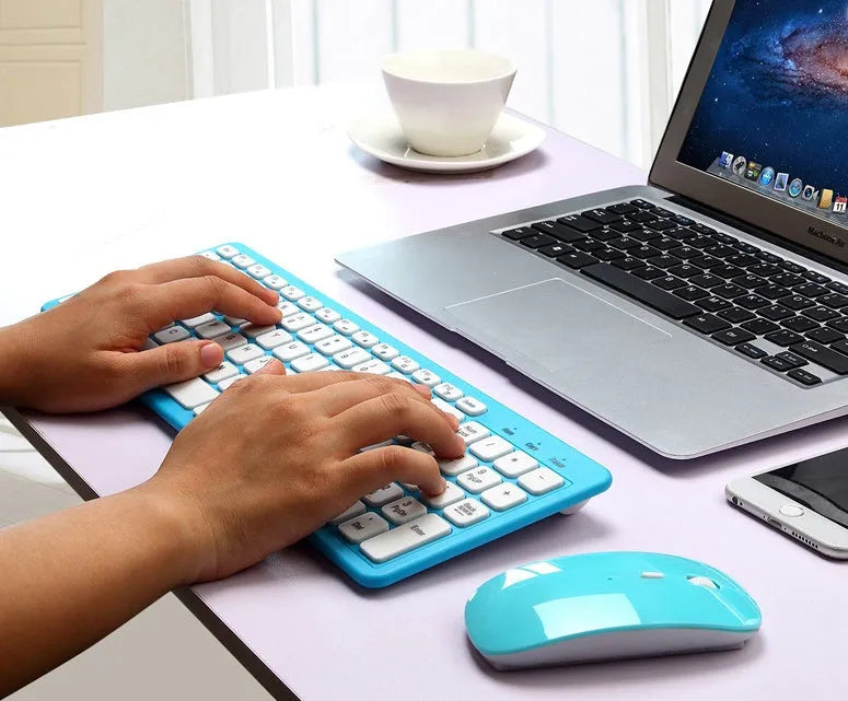 Black wireless keyboard and mouse set with USB receiver on a wooden desk.
