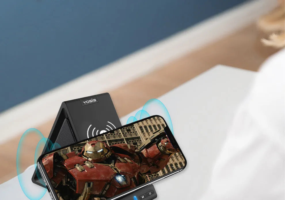 Black Bluetooth speaker with built-in stand holding a mobile phone on a desk.