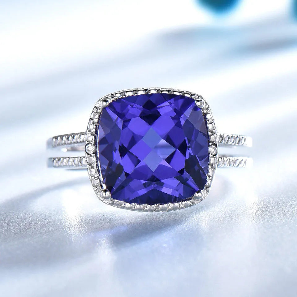 Blue Tanzanite stone set in a sterling silver women's ring on a plain background.