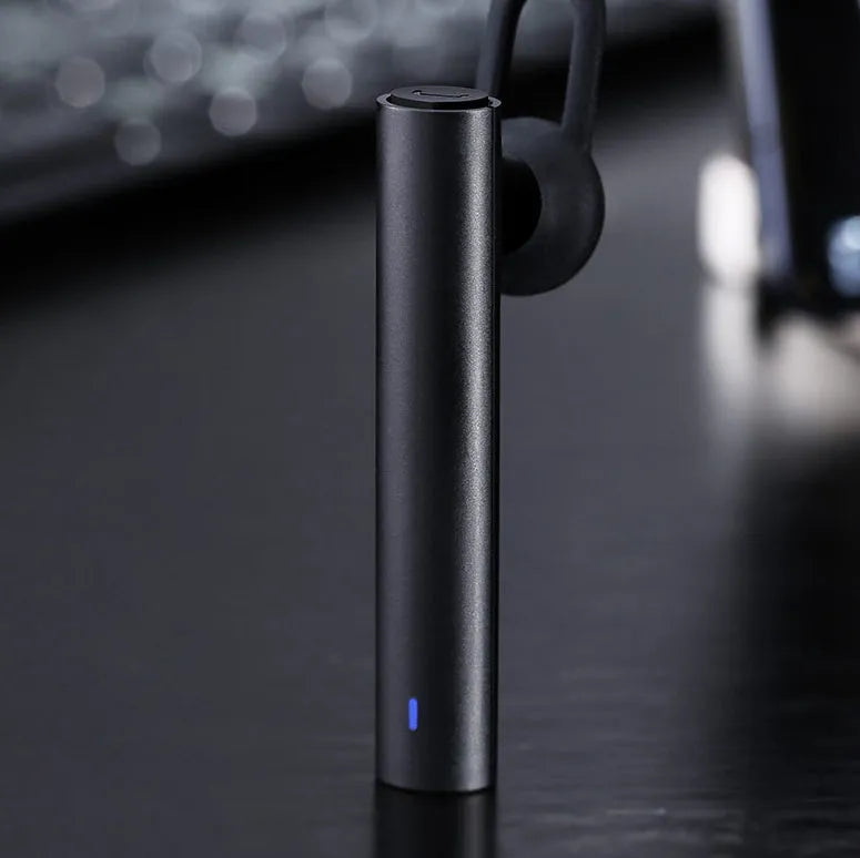 Compact black and white wireless Bluetooth headset for hands-free calls, shown next to a size scale.