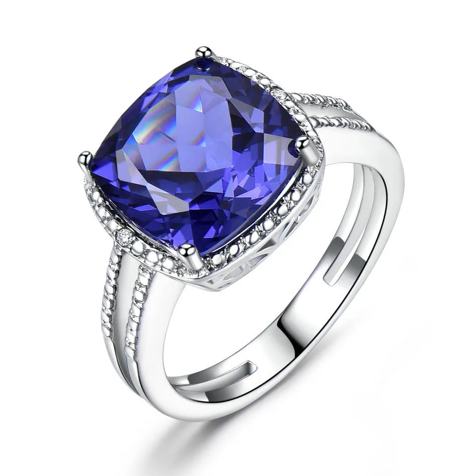 Blue Tanzanite stone set in a sterling silver women's ring on a plain background.