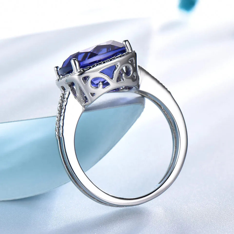 Blue Tanzanite stone set in a sterling silver women's ring on a plain background.