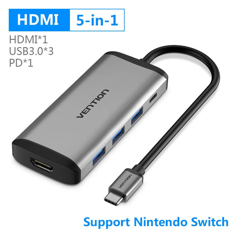 Deep grey USB-C to HDMI, USB 3.0, Ethernet, and card reader hub with a short cable on a desk.