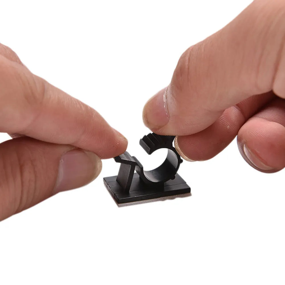 Black nylon adhesive cable clamps on a white background, showing self-adhesive backing and two-stage lock design.