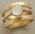 Gold-plated titanium steel ring with a white chalcedony stone in a hollow micro-inlaid geometric setting.