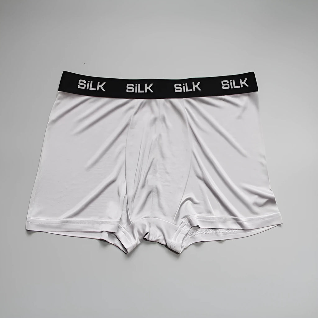 Men's loose-fit silk shorts in navy blue, shown on a mid-waist.