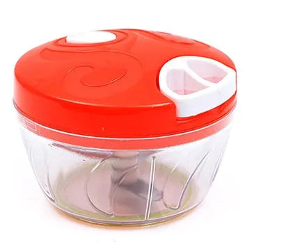 Green manual kitchen chopper with stainless steel blades next to chopped vegetables on a counter.
