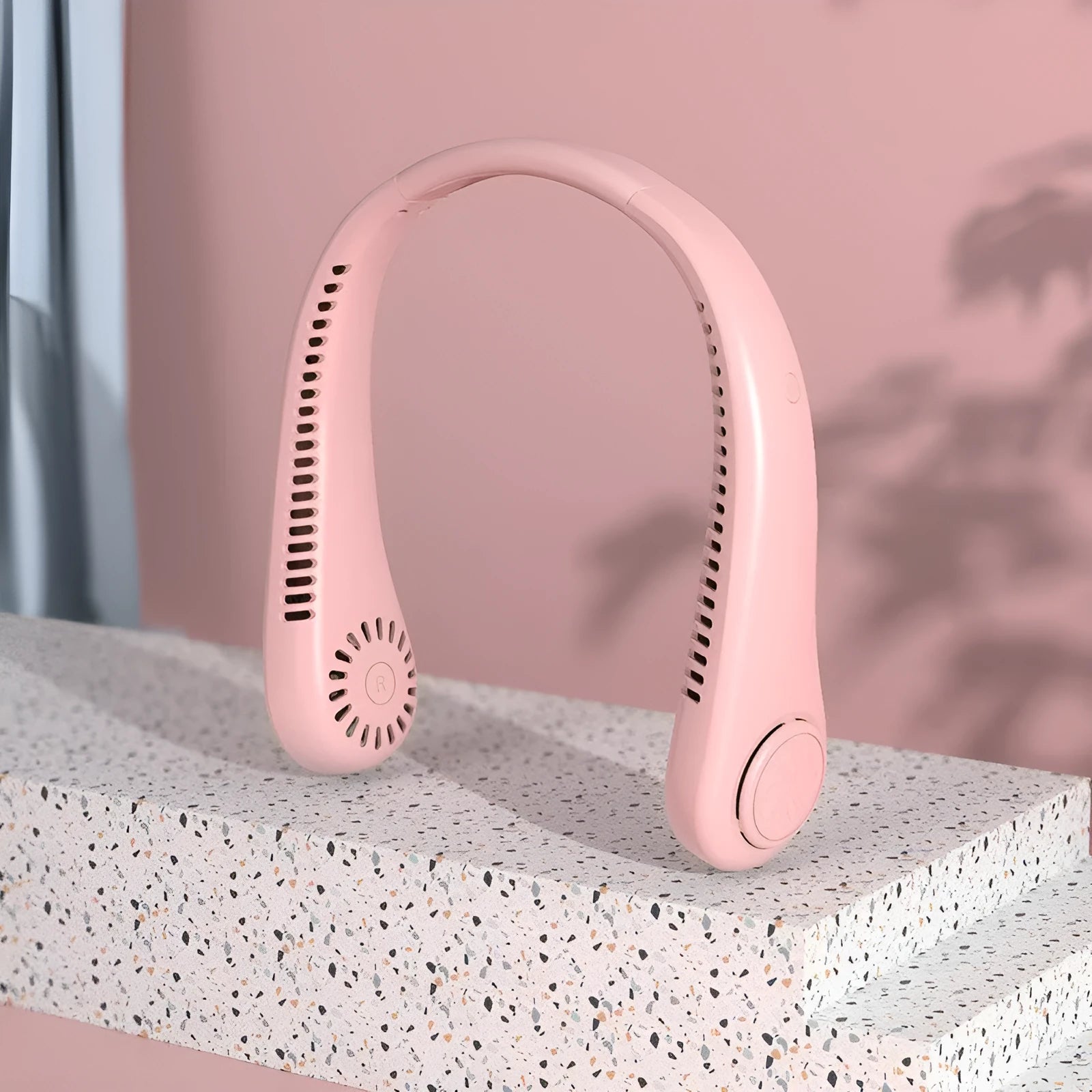 Pink portable bladeless neck fan hanging around a person's neck.
