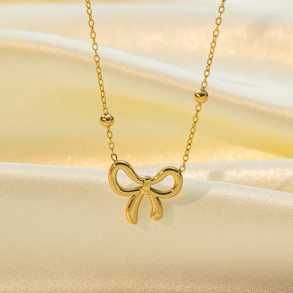 Gold bow necklace on a cross chain, adjustable from 41cm to 50cm length.