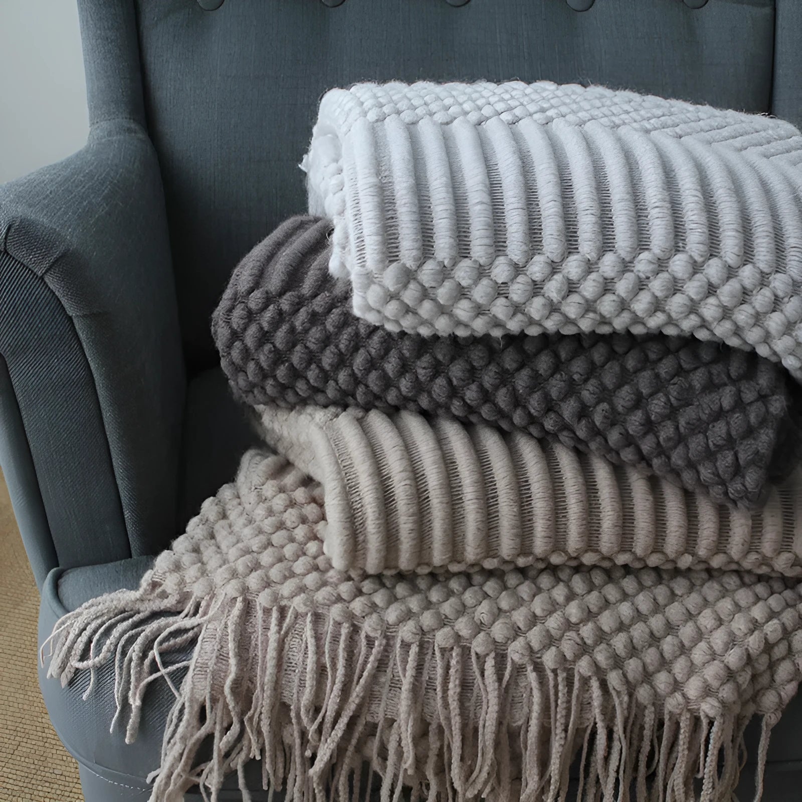 Small light grey polyester throw blanket folded on a sofa, showing its compact 127x170cm size.
