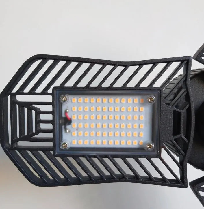 A foldable silver aluminium garage work lamp with a clear plastic lens, shown in an open position.