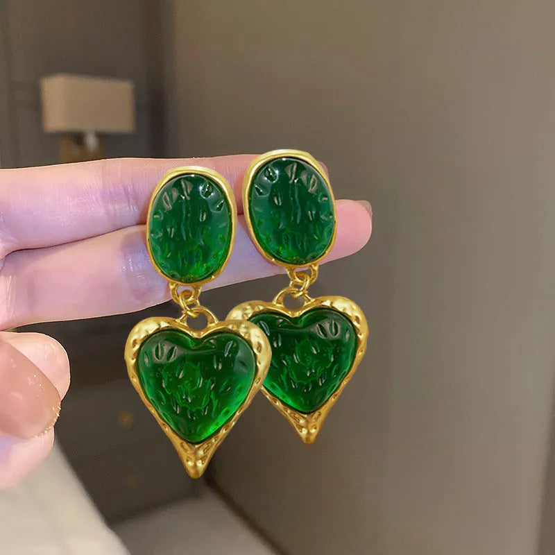 Oval heart-shaped alloy stud earrings with silver pleated edge, shown in purple, red, green, and yellow/white colour options.