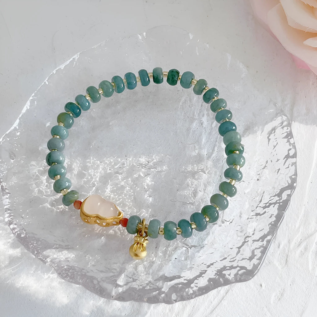 Women's jade bracelet with gourd shape, peace buckle charm, and strawberry quartz details in natural blue colours