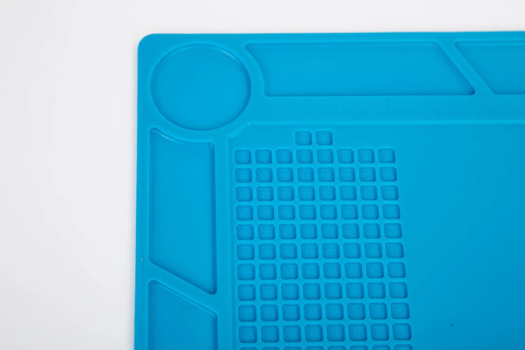 Blue silicone watch repair desk mat on a workbench, showing non-slip surface for watch components.