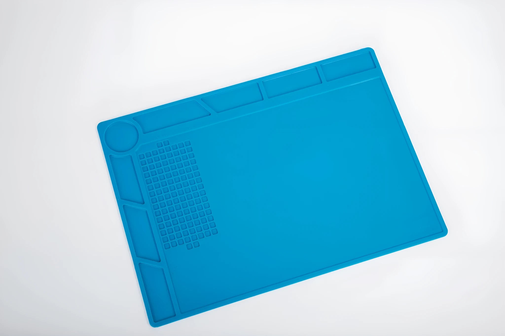 Blue silicone watch repair desk mat on a workbench, showing non-slip surface for watch components.