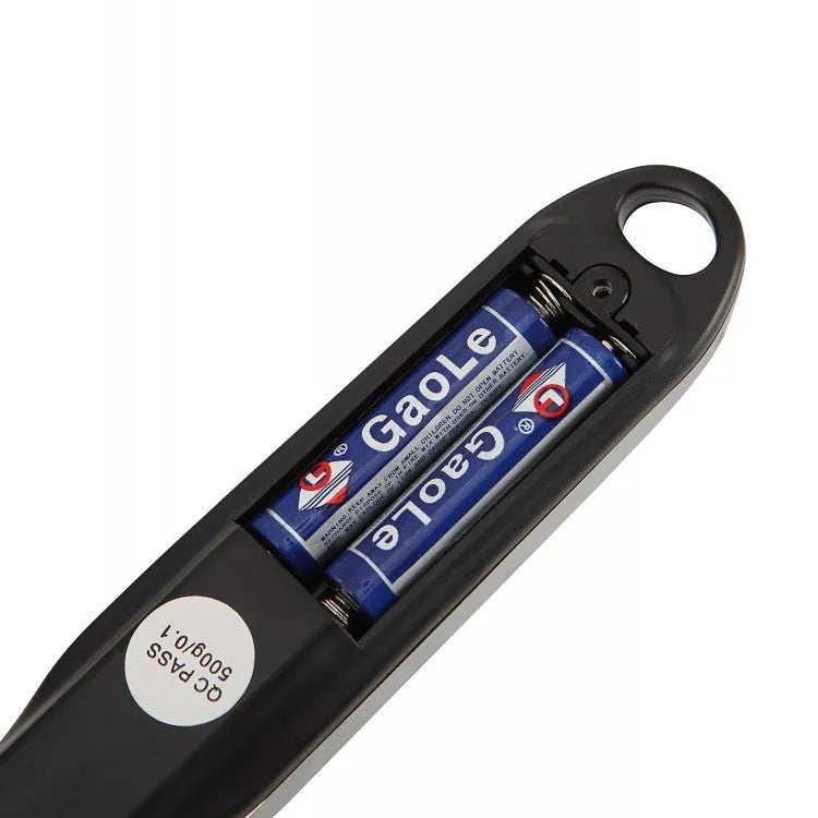 Smart digital measuring spoon with integrated display showing weight, next to AAA batteries.