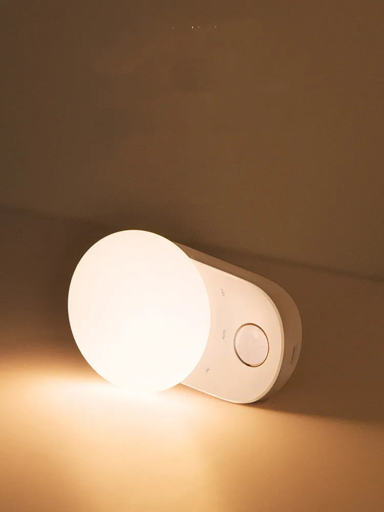 White Baseus rechargeable motion sensor night light on a bedside table.