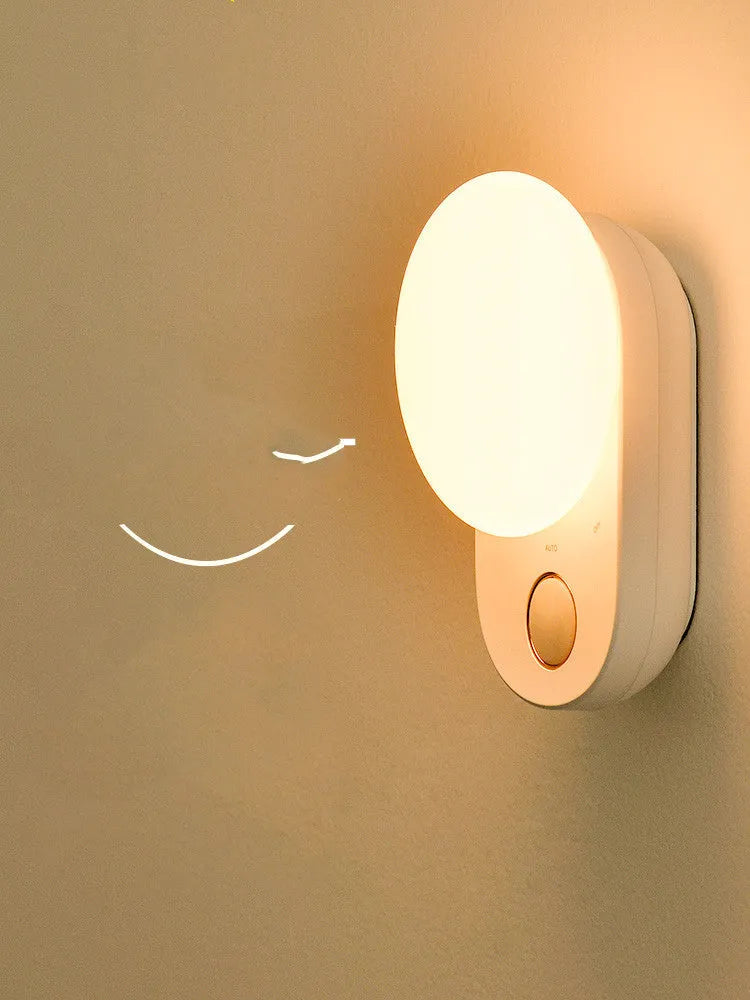 White Baseus rechargeable motion sensor night light on a bedside table.