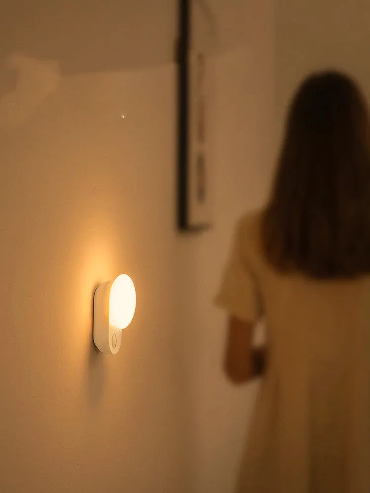 White Baseus rechargeable motion sensor night light on a bedside table.