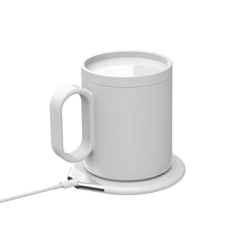 Black wireless charging warm cup on desk next to smartphone, showing USB cable.