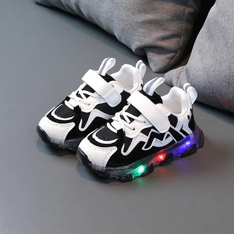 Children's sneakers with Velcro strap, mesh upper panels, and a solid rubber sole in black, grey, or pink.