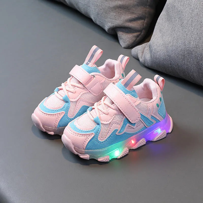 Children's sneakers with Velcro strap, mesh upper panels, and a solid rubber sole in black, grey, or pink.