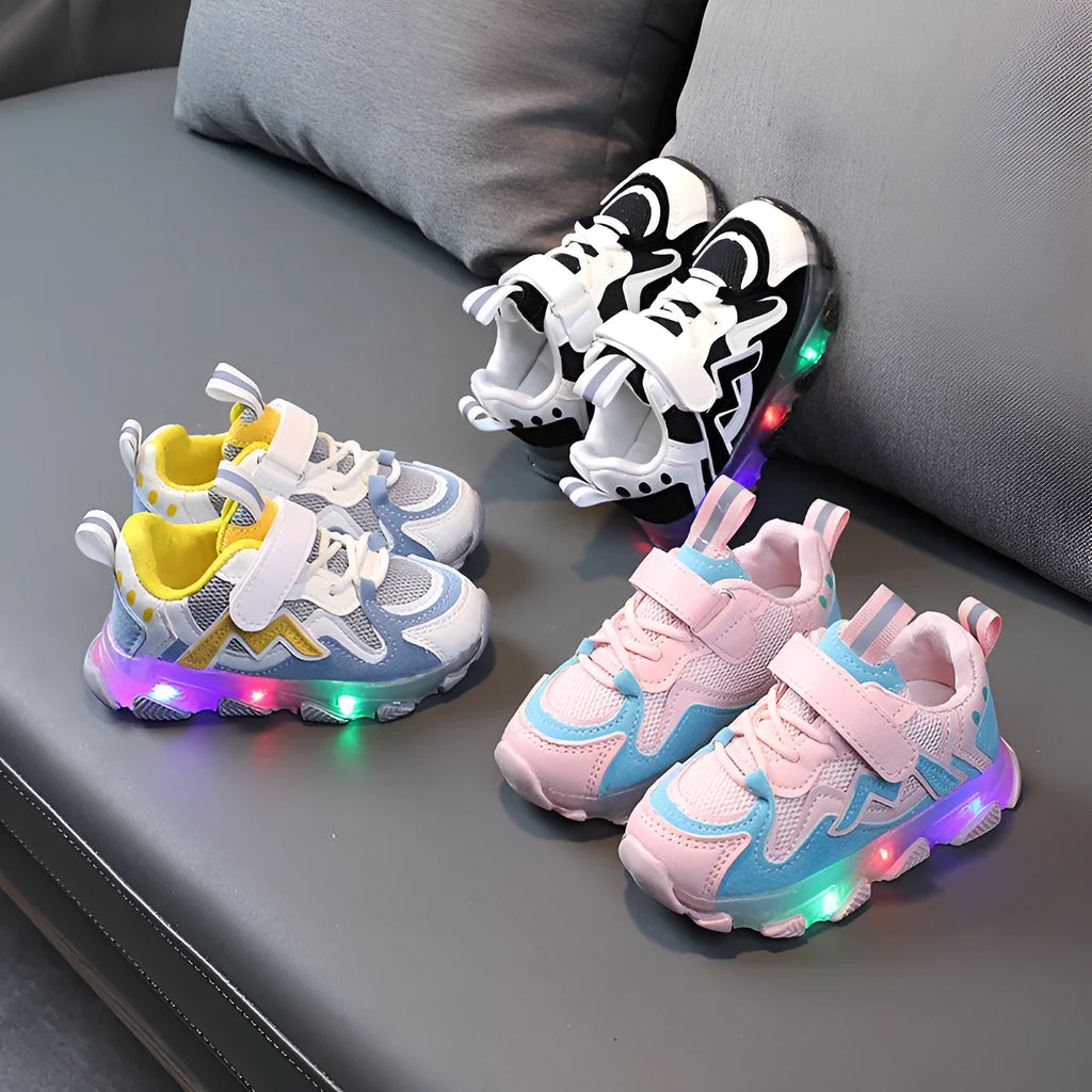 Children's sneakers with Velcro strap, mesh upper panels, and a solid rubber sole in black, grey, or pink.