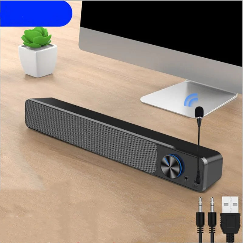 Compact black and white desktop computer speaker with audio and USB cables on a wooden desk.