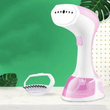 Mini portable handheld garment steamer 1200W in pink with water tank and brush on a wooden surface
